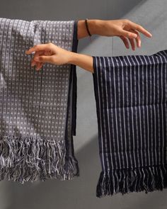 a woman's hand is reaching out from behind two black and white striped towels