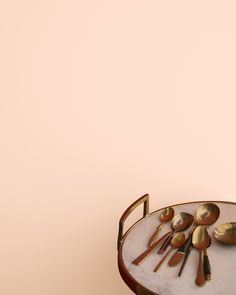 spoons and utensils sit on a table against a pink background with gold accents