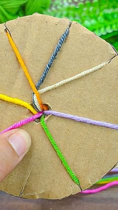 a person is holding an umbrella made out of paper and twined with colored thread