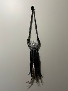 a black and white dream catcher hanging from the wall with feathers on it's back