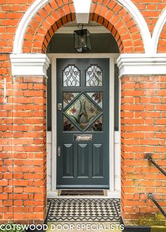 a black and white checkered door in front of a red brick building with arched windows