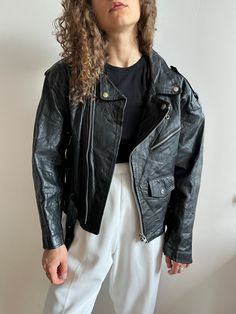 Vintage 90s genuine leather biker/motorcycle jacket in black, polyester lining, gender neutral, fits XS-M, two side pockets, with a belt, leather is very stiff, oversized/loose fit, good vintage condition, slightly distressed Great for casual & minimalistic looks. Measurements Shoulders 46 cm / 18.1" Sleeve 58 cm / 22.8" Length 59 cm / 23.2" Bust from armpit to armpit 46 cm / 18.1" Model’s height 166 cm / 65.4" Black Leather Jacket For Winter In Grunge Style, Black Moto Biker Jacket For Alternative Fashion, Black Grunge Leather Jacket For Winter, Black Grunge Leather Jacket For Spring, Black Grunge Biker Jacket For Fall, Black Leather Grunge Jacket For Streetwear, Black Grunge Leather Jacket For Streetwear, Black Zipper Closure Grunge Outerwear, Black Grunge Outerwear With Zipper Closure