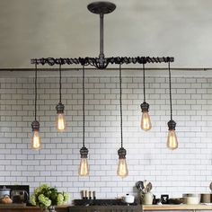 a bunch of light bulbs hanging from the ceiling in a kitchen with white brick walls