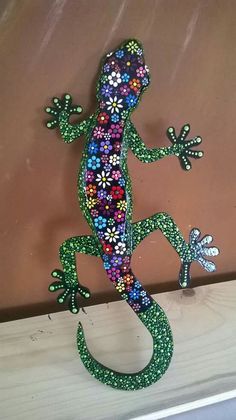 a lizard made out of beads sitting on top of a wooden table next to a wall