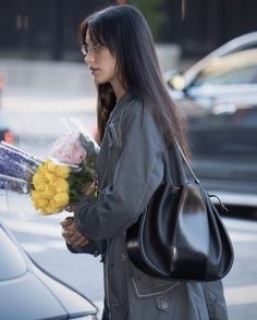 a woman holding flowers standing next to a car