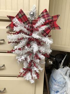 a red and white christmas decoration hanging from the side of a cabinet