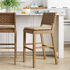 two wooden stools sitting in front of a white counter top next to a potted plant