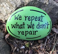 a green rock with the words we repeat what we don't repair written on it