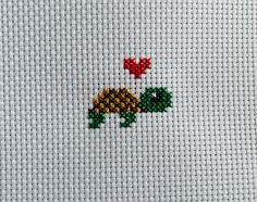 a cross stitch pattern with a turtle and two red flowers on the left hand side