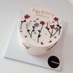 a white cake with flowers on it sitting on top of a paper napkin that says happy birthday cuties