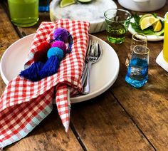 the table is set with plates, silverware, and colorful napkins on it