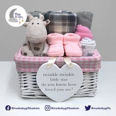 a baby gift basket with booties, blankets and a stuffed giraffe in it