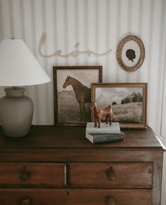 a dresser with two pictures and a horse figurine sitting on top of it