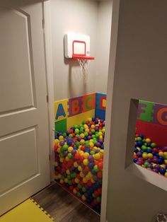 there is a basketball hoop in the corner of this kids's playroom with balls all over the floor