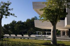 a large white building sitting next to a lush green park filled with lots of trees