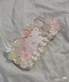 a cell phone case with flowers and pearls on the back is laying on a white sheet