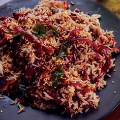 a black plate topped with rice and veggies