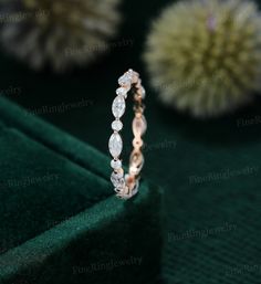 a diamond ring sitting on top of a green velvet covered table next to a flower