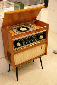 an old fashioned record player sitting on top of a wooden stand next to a wall