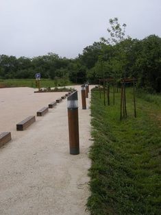 several wooden posts are lined up along the path in an open area with grass and dirt