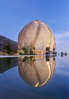 an unusual building is reflected in the water