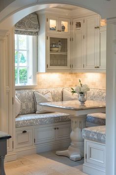 a kitchen with white cabinets and marble counter tops, along with an arched doorway leading to the dining room