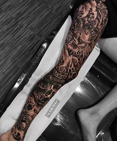 a man's arm with a tiger and skulls tattoo on the left side of his leg