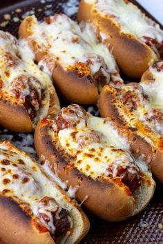 several hot dogs covered in cheese and sauce