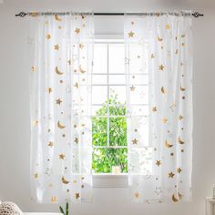 a window with stars and crescents on it in front of a white chair next to a potted plant