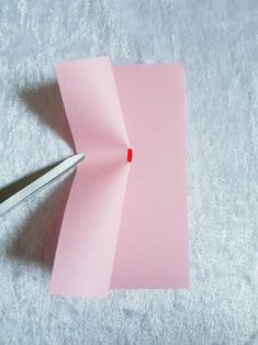 a pink piece of paper sitting next to a pair of scissors