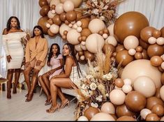 three women sitting on a couch surrounded by balloons