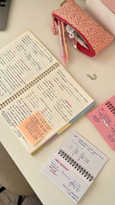 an open notebook sitting on top of a desk next to a computer keyboard and pencils