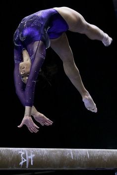 a woman is performing on the balance beam