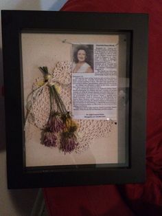 a framed photo with flowers on it in front of a red chair and a pillow