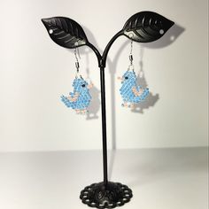 a pair of earrings with blue beads hanging from them on a black metal stand against a white wall