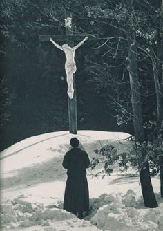 a woman standing in the snow next to a crucifix