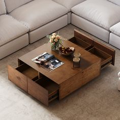 a coffee table with drawers on top in front of a white couch and two chairs