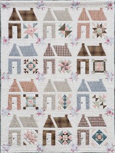 a quilted wall hanging with houses and flowers on the front, in pastel colors