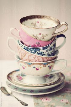 a stack of tea cups and saucers sitting on top of each other next to a spoon