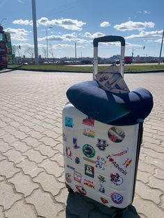 a piece of luggage with stickers on it sitting in the middle of a parking lot