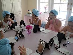 several women sitting at a table with their hands on their mouths and wearing blue towels