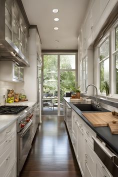 a narrow kitchen with white cabinets and black counter tops, along with hardwood flooring