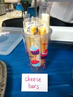 there is a plastic cup with some food in it and a sign that says cheese bars