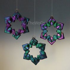 three colorful ornaments hanging from strings on a wall