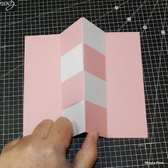 someone is cutting out a pink and white piece of paper