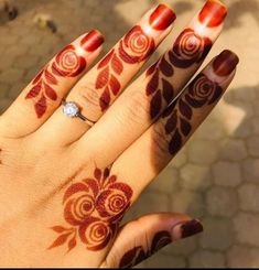 a woman's hand with red and white henna tattoos on her left hand