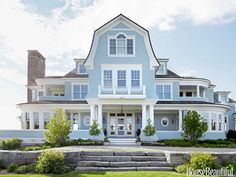 a large blue house sitting on top of a lush green field