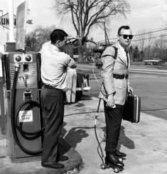 two men standing next to each other at a gas pump