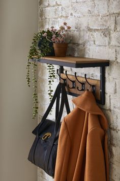 a coat rack with two coats hanging from it's sides and a purse next to it