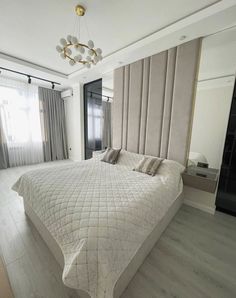 a large white bed sitting inside of a bedroom next to a window covered in curtains